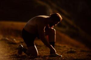 A determined athlete preparing for the start of training on the top of the mountain at sunrise. photo