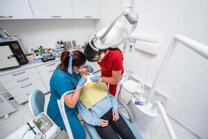 Dentist appointment at a dental clinic, placing braces locks on the teeth and pulling the archwire to fix it photo