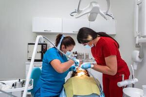 Dentist appointment at a dental clinic, placing braces locks on the teeth and pulling the archwire to fix it photo