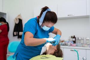 Dentist appointment at a dental clinic, placing braces locks on the teeth and pulling the archwire to fix it photo
