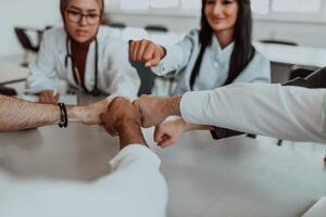 A group of doctors and a medical nurse join their hands together on a table, showcasing the unwavering teamwork and solidarity that drives their collective efforts in the healthcare field photo