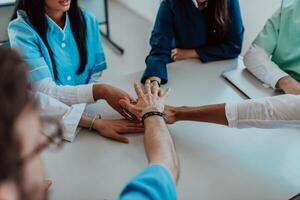 A group of doctors and a medical nurse join their hands together on a table, showcasing the unwavering teamwork and solidarity that drives their collective efforts in the healthcare field photo