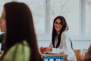 A black-haired female student wearing glasses is attentively engaged in a modern classroom, embracing education and learning with focus and curiosity photo