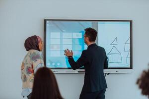 A modernly dressed professor engages in educating students, who listen attentively, creating a dynamic scene of knowledge-sharing and focused learning in the classroom. photo