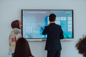 A modernly dressed professor engages in educating students, who listen attentively, creating a dynamic scene of knowledge-sharing and focused learning in the classroom. photo