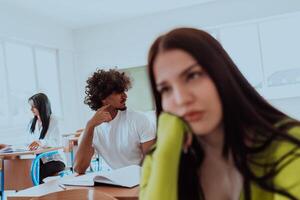 A weary-looking student sitting in front of a group of diverse students in a modern classroom, capturing the blend of exhaustion, learning, and collaboration in their academic journey photo