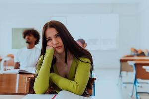 A weary-looking student sitting in front of a group of diverse students in a modern classroom, capturing the blend of exhaustion, learning, and collaboration in their academic journey photo