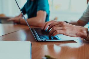 In a close-up view, the fingers of a man are seen typing swiftly on a laptop keyboard, depicting a scene of focused productivity in a digital work environment photo