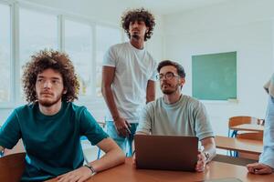 A diverse studetns group, including an Afro American with an afro hairstyle communicating and engage with their colleague while seated in a modern classroom, collectively focused on a laptop. photo