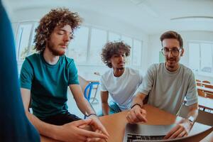 A diverse studetns group, including an Afro American with an afro hairstyle communicating and engage with their colleague while seated in a modern classroom, collectively focused on a laptop. photo