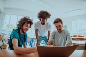 A diverse studetns group, including an Afro American with an afro hairstyle communicating and engage with their colleague while seated in a modern classroom, collectively focused on a laptop. photo
