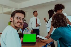 A group of business colleagues exchange knowledge and insights while utilizing laptops in the office, showcasing collaborative learning, effective communication, and a dynamic corporate environment photo