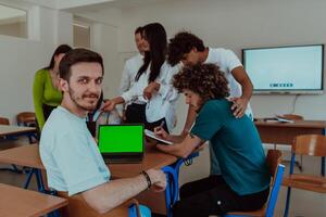 A group of business colleagues exchange knowledge and insights while utilizing laptops in the office, showcasing collaborative learning, effective communication, and a dynamic corporate environment photo