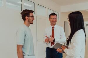 The director conducts a conversation with the secretary and a young programmer in a modern and spacious corridor of a large company, discussing various business topics and projects. photo