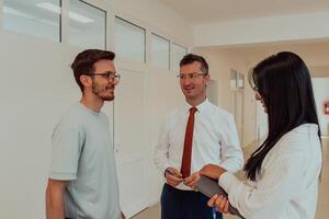 The director conducts a conversation with the secretary and a young programmer in a modern and spacious corridor of a large company, discussing various business topics and projects. photo