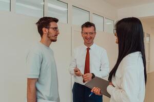 The director conducts a conversation with the secretary and a young programmer in a modern and spacious corridor of a large company, discussing various business topics and projects. photo