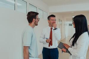 The director conducts a conversation with the secretary and a young programmer in a modern and spacious corridor of a large company, discussing various business topics and projects. photo