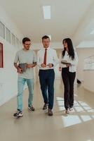 The director conducts a conversation with the secretary and a young programmer in a modern and spacious corridor of a large company, discussing various business topics and projects. photo