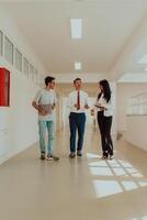 The director conducts a conversation with the secretary and a young programmer in a modern and spacious corridor of a large company, discussing various business topics and projects. photo