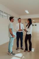 The director conducts a conversation with the secretary and a young programmer in a modern and spacious corridor of a large company, discussing various business topics and projects. photo