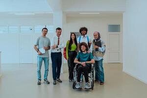 A group of students with a professor and a colleague who is in a wheelchair are standing together in the corridor of a modern university photo