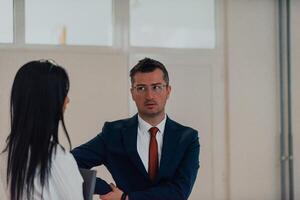 The director conducts a conversation with the secretary and a young programmer in a modern and spacious corridor of a large company, discussing various business topics and projects. photo