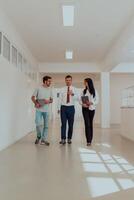 The director conducts a conversation with the secretary and a young programmer in a modern and spacious corridor of a large company, discussing various business topics and projects. photo