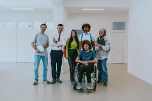 A group of students with a professor and a colleague who is in a wheelchair are standing together in the corridor of a modern university photo