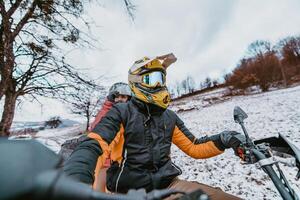 A young adventurous couple embraces the joy of love and thrill as they ride an ATV Quad through the snowy mountainous terrain photo