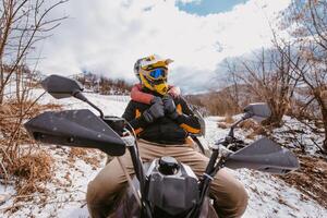 A young adventurous couple embraces the joy of love and thrill as they ride an ATV Quad through the snowy mountainous terrain photo