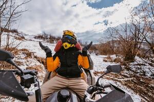 A young adventurous couple embraces the joy of love and thrill as they ride an ATV Quad through the snowy mountainous terrain photo