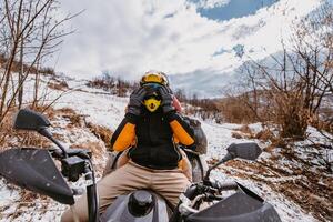 A young adventurous couple embraces the joy of love and thrill as they ride an ATV Quad through the snowy mountainous terrain photo