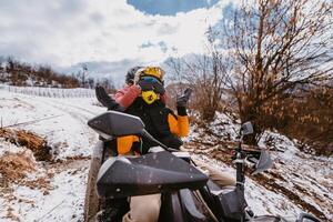 A young adventurous couple embraces the joy of love and thrill as they ride an ATV Quad through the snowy mountainous terrain photo
