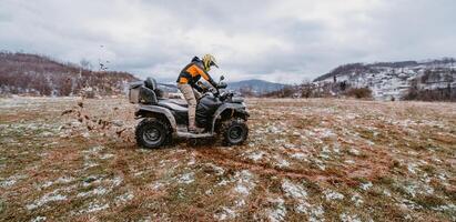 A man is fearlessly enjoying an adventurous ride on an ATV Quad through hazardous snowy terrain, embracing the thrill and excitement of the challenging mountainous landscape photo