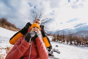 A young adventurous couple embraces the joy of love and thrill as they ride an ATV Quad through the snowy mountainous terrain photo