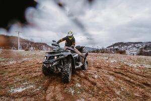 A man is fearlessly enjoying an adventurous ride on an ATV Quad through hazardous snowy terrain, embracing the thrill and excitement of the challenging mountainous landscape photo