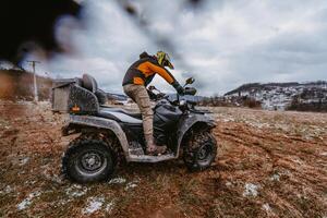 A man is fearlessly enjoying an adventurous ride on an ATV Quad through hazardous snowy terrain, embracing the thrill and excitement of the challenging mountainous landscape photo