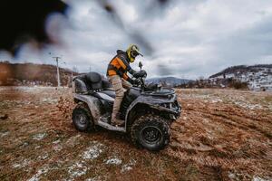A man is fearlessly enjoying an adventurous ride on an ATV Quad through hazardous snowy terrain, embracing the thrill and excitement of the challenging mountainous landscape photo