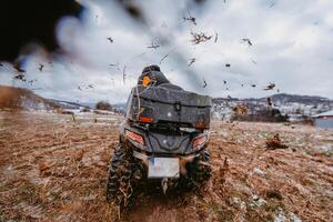 A man is fearlessly enjoying an adventurous ride on an ATV Quad through hazardous snowy terrain, embracing the thrill and excitement of the challenging mountainous landscape photo