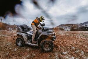 A man is fearlessly enjoying an adventurous ride on an ATV Quad through hazardous snowy terrain, embracing the thrill and excitement of the challenging mountainous landscape photo