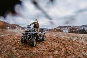 A man is fearlessly enjoying an adventurous ride on an ATV Quad through hazardous snowy terrain, embracing the thrill and excitement of the challenging mountainous landscape photo