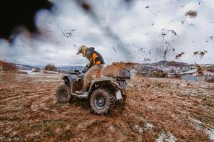 A man is fearlessly enjoying an adventurous ride on an ATV Quad through hazardous snowy terrain, embracing the thrill and excitement of the challenging mountainous landscape photo