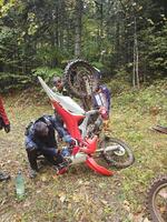A group of bikers encounters a motorcycle breakdown deep in the forest, tackling the technical challenge in this extreme and authentic outdoor scene photo