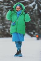 In the breathtaking snowy mountains, a beautiful woman in a hijab and green jacket poses with grace, blending modesty and style in the winter landscape photo