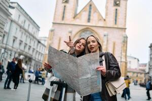 Two female tourists engage in lively discussion, surrounded by their luggage, as they plan their sightseeing journey through the bustling city streets, map in hand. photo