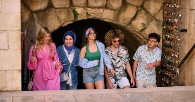 A diverse group of tourists, dressed in summer attire, strolls through the tourist city with wide smiles, enjoying their sightseeing adventure photo