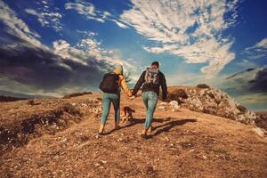 happy couple man and woman tourist at top of mountain during a hike in summer photo