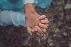Close up photo the hands of a romantic couple are intimately entwined beneath the water's surface, capturing the tactile and aquatic essence of their love in a sensory embrace