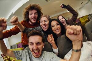 A diverse group of young people exuberantly celebrates and cheers while watching a soccer match, radiating excitement, unity, and sportsmanship photo