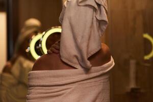 A woman gracefully applies nourishing moisturizer to her shoulder after a relaxing bath, embodying a radiant and rejuvenated skincare routine photo